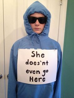 a man in a blue hoodie holding a sign that says she doesn't even go here