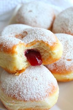 powdered doughnuts with jelly filling on white plate