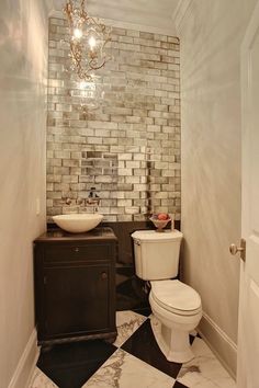 a white toilet sitting next to a sink in a bathroom under a chandelier