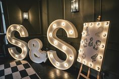 the letters s and s are lit up in white light bulbs, with an easel next to it