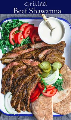 grilled beef shawarma on a plate with tomatoes, lettuce and onions