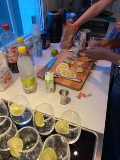 several glasses and lemons are on the counter with ingredients for making margarita cocktails