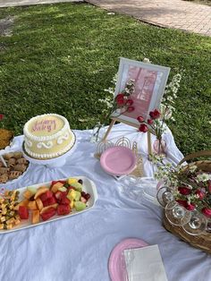 a table topped with lots of food on top of a white tablecloth covered field