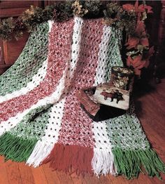 a crocheted blanket is sitting on the floor next to a pile of books