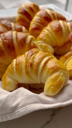 croissants are sitting on a towel in front of someone's hand