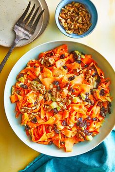 a white bowl filled with pasta and nuts next to a plate of food on top of a blue towel