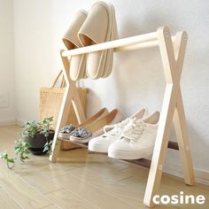 two pairs of shoes are sitting on a wooden rack next to a plant and basket