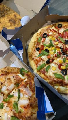 two pizzas in boxes with different toppings on them and one has been cut into slices