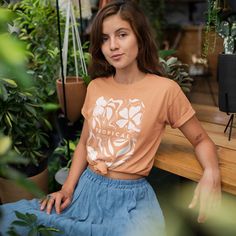 a woman is sitting on a bench in front of some potted plants and looking at the camera