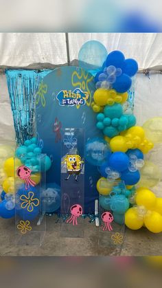 the balloon arch is decorated with blue, yellow and white balloons