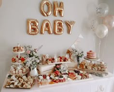 a baby shower table filled with food and balloons