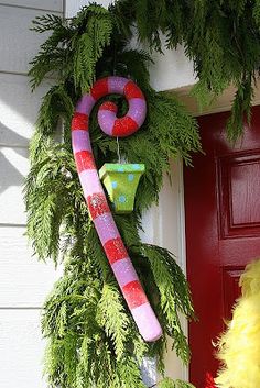 a christmas wreath with candy canes and other holiday decorations hanging on the front door