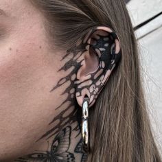 a woman with tattoos on her neck and behind the ear is a pair of scissors