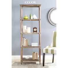 a wooden shelf with books and vases on it in a blue living room next to a white chair