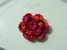 a small crocheted flower sitting on top of a white table next to a knife