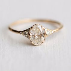 an engagement ring with two pear shaped diamonds on the side, set in yellow gold