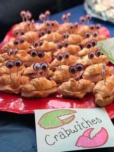 croissants with googly eyes are on a red plate next to a sign that says crabbitches