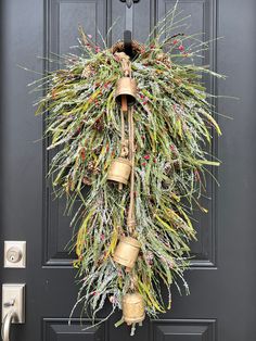 a wreath hanging on the front door with bells and evergreens attached to it's sides