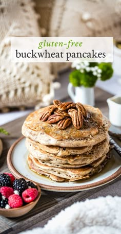 a stack of pancakes sitting on top of a white plate next to berries and nuts