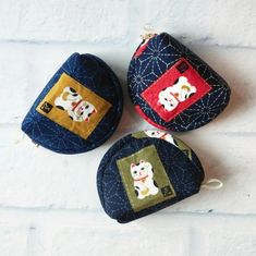 three small purses with dogs on them sitting next to each other in front of a white brick wall