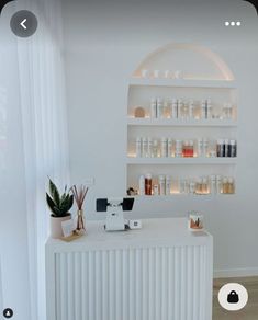 a white counter topped with lots of bottles next to a wall mounted shelf filled with candles