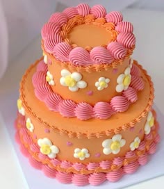 a three tiered cake with pink icing and white flowers