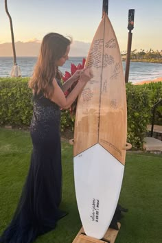 a woman standing next to a surfboard in the grass