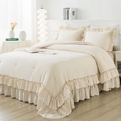 a white bed with ruffled sheets and pillows