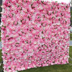 a pink and white flowered wall in the grass