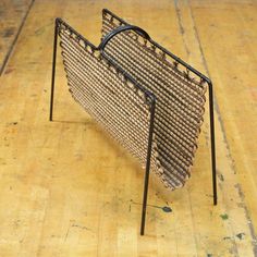 a woven purse sitting on top of a wooden floor next to a black metal frame