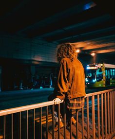 a person standing on a railing looking at a bus