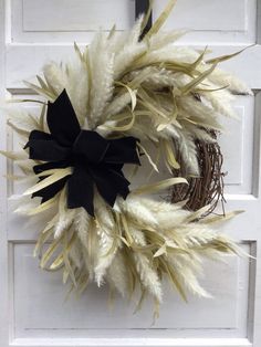 a white door with a black bow and some feathers on the front door, hanging from it's side