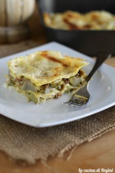 a piece of lasagna on a plate with a fork and pan in the background