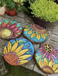 four decorated cookies sitting on top of a wooden table next to potted plants and flowers