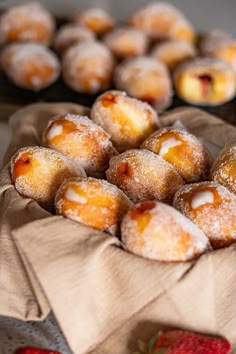 powdered sugar covered donuts and strawberries on a table