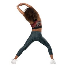 a woman in black and red sports bra top standing on one leg with her hands behind her head