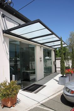 a car parked in front of a building with a glass roof over the entrance to it