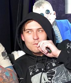 a man in a black hoodie is holding his finger to his mouth