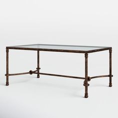 a glass top table with metal legs and an iron frame on the bottom, against a white background