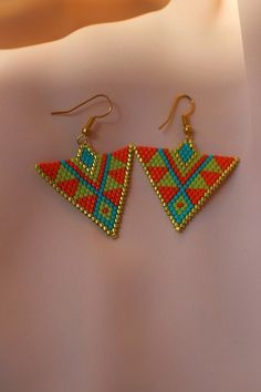 a pair of earrings with beaded designs on them sitting on top of a white surface