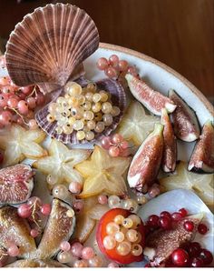 an assortment of fruits and vegetables on a platter with seashells, starfish, and tomatoes