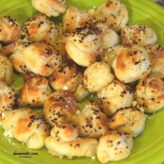 a green plate topped with mini rolls covered in cheese and black pepper sprinkles