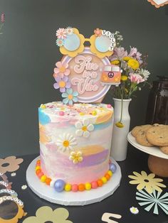 a decorated cake on a table with cookies and flowers