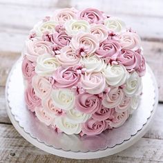 a cake with pink and white frosting flowers on it sitting on top of a plate