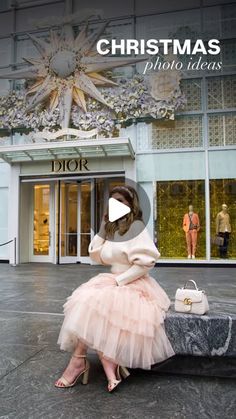 a woman sitting on a bench in front of a building wearing a pink tulle skirt