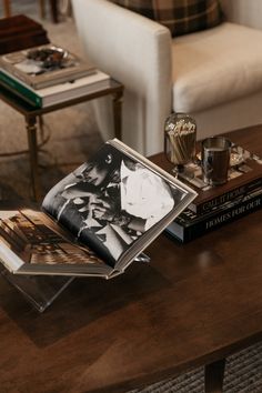 a coffee table with two books on it next to a white couch and some chairs