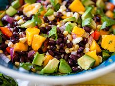 a salad with black beans, mangoes and avocado in a blue bowl