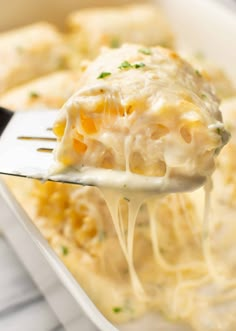 a fork full of pasta and cheese being lifted from a casserole dish