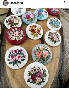 a wooden table topped with lots of different types of embroidered flowers on top of buttons