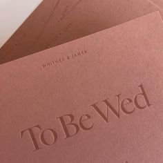 three pink books with the words to be wed written in brown ink on top of them